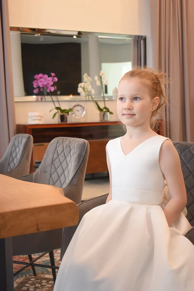 Ivory satin flower girl dress with V-neckline and wide waistband, full ball gown skirt, pockets visible